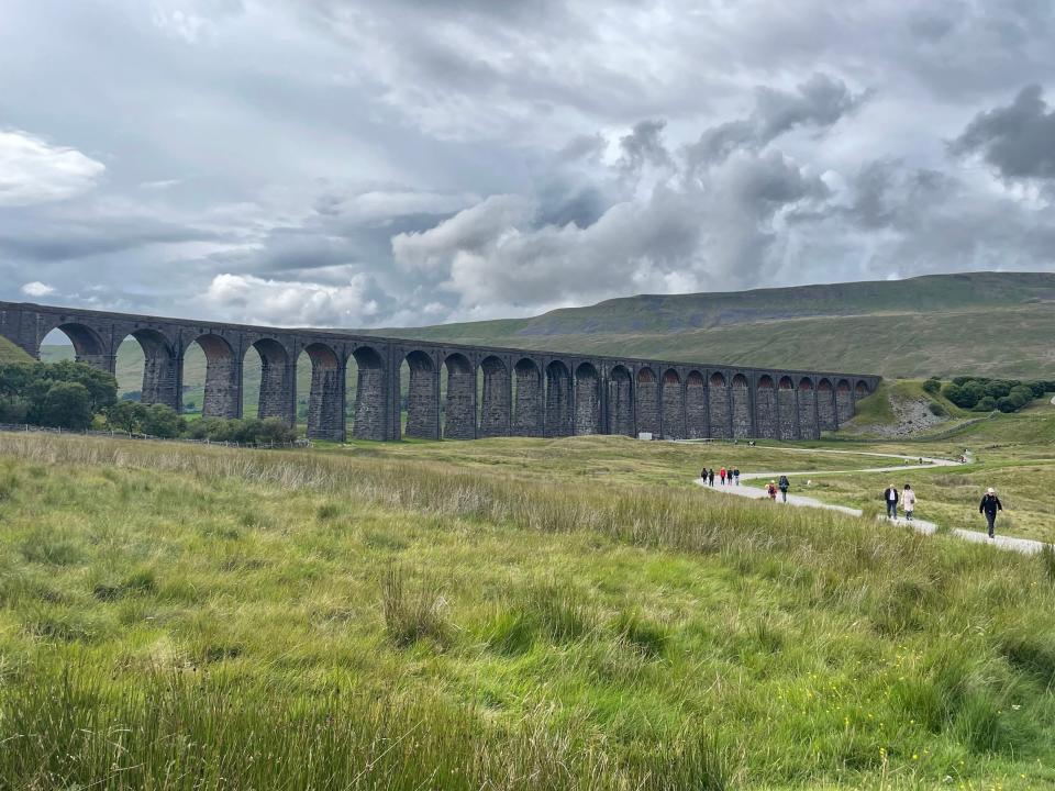 The Ribblehead Viaduct, a Victorian Railway Bridge, in the middle of the hiking trail in a cloudy day.