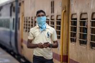 A passenger wearing a facemask amid concerns over the spread of the COVID-19 novel coronavirus waits on a platform to board a train at a railway station in Secunderabad, the twin city of Hyderabad, on March 20, 2020. (Photo by NOAH SEELAM / AFP) (Photo by NOAH SEELAM/AFP via Getty Images)