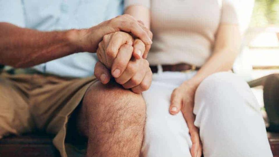 Close up shot of senior couple holding hand. Loving couple sitting together and holding hands. Focus on hands.