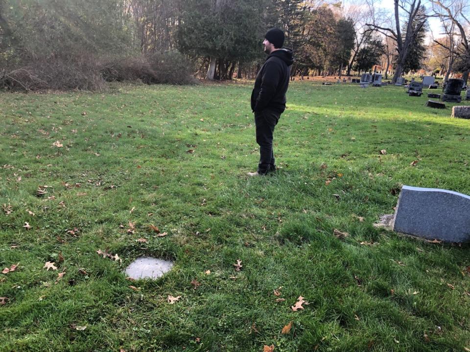 Assistant Superintendent Kyle Waterman of Forest Hill Cemetery in Utica stands in the area where officials believe the disinterred remains of people once buried in Potter's Field Cemetery in Utica were reburied in 1916 without any markers. The flat marker on the left is for John Jones, who died in 1849 and was originally buried in Potter's Field. Forest Hill staff tracked down the approximate site of his grave on behalf of his great-great-great-granddaughter Nancy West of Rocky Mount, North Carolina.