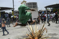 A person jumps over a bonfire on the street as members of the gang led by Jimmy Cherizier, alias Barbecue, a former police officer who heads a gang coalition known as "G9 Family and Allies," march to demand justice for slain Haitian President Jovenel Moise in La Saline neighborhood of Port-au-Prince, Haiti, Monday, July 26, 2021. Moise was assassinated on July 7 at his home. (AP Photo/Matias Delacroix)