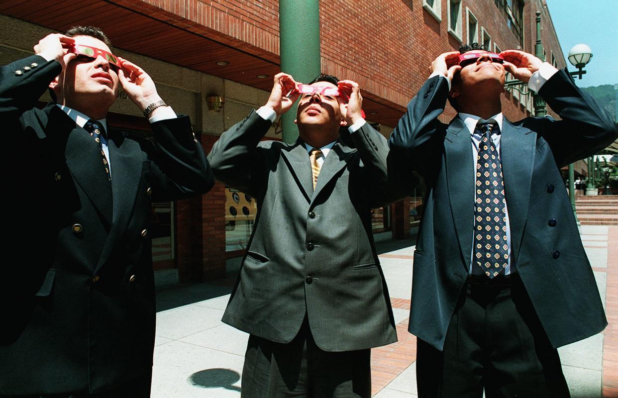1998: Men in suits watch a total solar eclipse visible through special glasses in downtown Bogota, Colombia. 