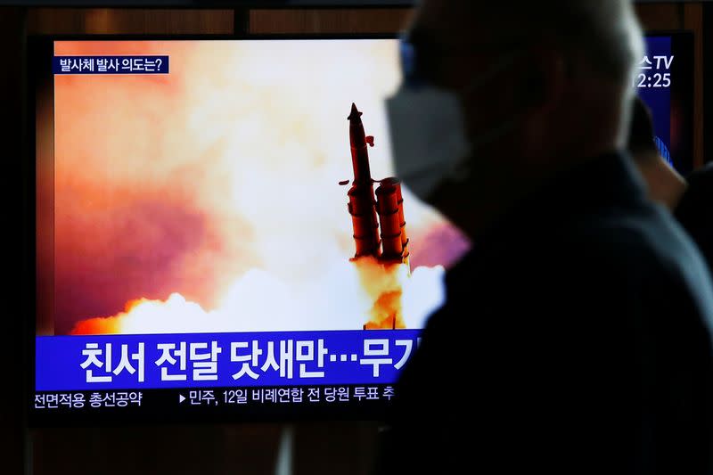 A man walks past a TV broadcasting file footage for a news report on North Korea firing an unidentified projectile, in Seoul