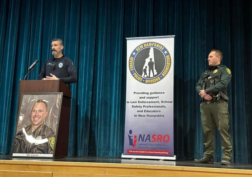 NH Juvenile Police Officer Association board member Richard Addonizio gives Hampton police Detective and school resource officer Zach Terenzoni the organization's first annual special recognition award during the surprise special assembly at Hampton Academy March 12.