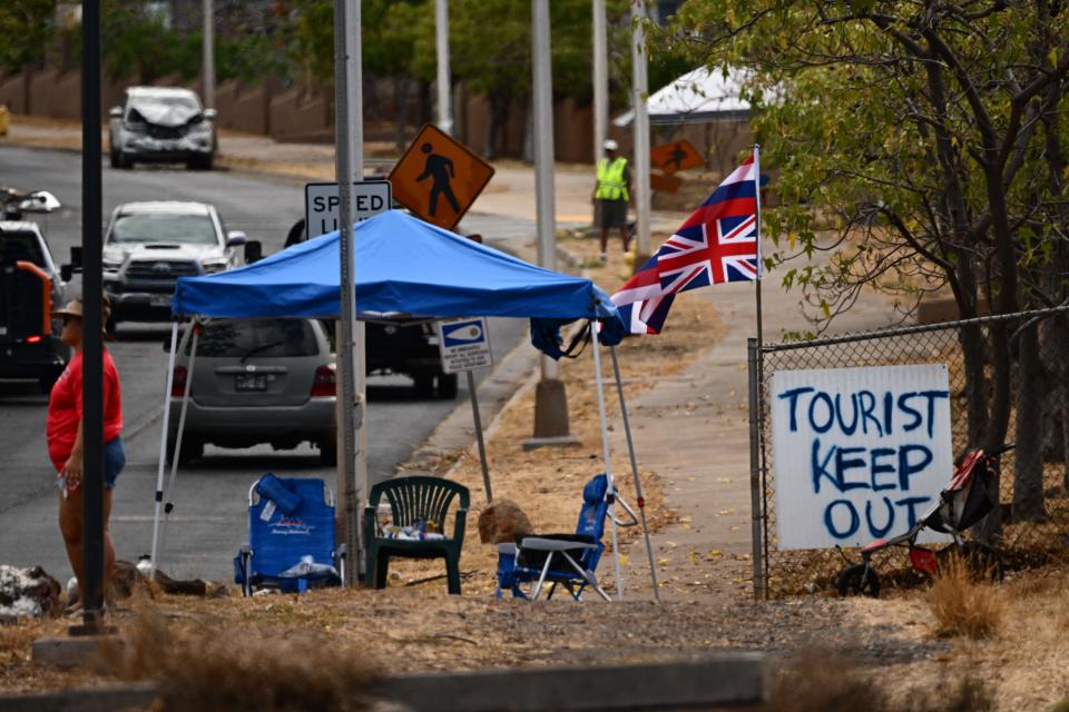 The Flag of Hawaii waves by a sign reading 