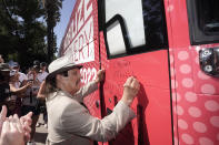 Actor Danny Trejo signs the 2022 Mobile Recovery National Bus during a stop at the Capitol in Sacramento, Calif. Sept. 7, 2022. Trejo spoke at the recovery rally telling the crowd about his past problems with drug addiction. Across the country, people in recovery and relatives of those killed by opioid overdoses are pressing for roles in determining how billions in opioid settlement money will be used. That push is one of the missions of the monthlong nationwide bus tour. (AP Photo/Rich Pedroncelli)