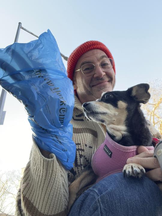 This photo shows Jono Waks of Brooklyn with his dog, Millie. Waks recycles his plastic newspaper wrappers to clean up after his dog. There are myriad steps individuals can take to lead more sustainable lives. (Jono Waks via AP).