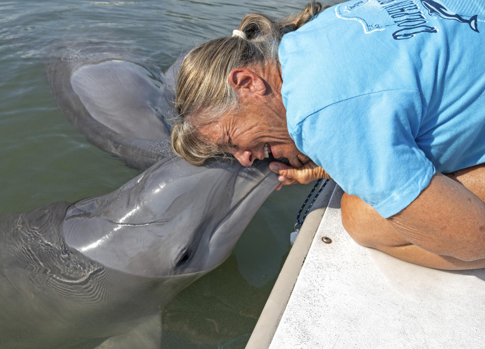 In this photo provided by the Florida Keys News Bureau, Linda Erb, vice president of animal care and training at Dolphin Research Center in the Florida Keys, hugs Ranger at DRC Monday, March 27, 2023, in Marathon, Fla. Bottlenose dolphin Ranger, now three years old, was airlifted to the Florida Keys one year ago from Texas, after being discovered stranded in waters around Goose Island State Park suffering from a respiratory infection and dehydration. He was deemed too young to forage and survive in the wild, and the National Marine Fisheries Service selected DRC as his forever home. Ranger is thriving and socializing with other dolphins at the center. (Andy Newman/Florida Keys News Bureau via AP)