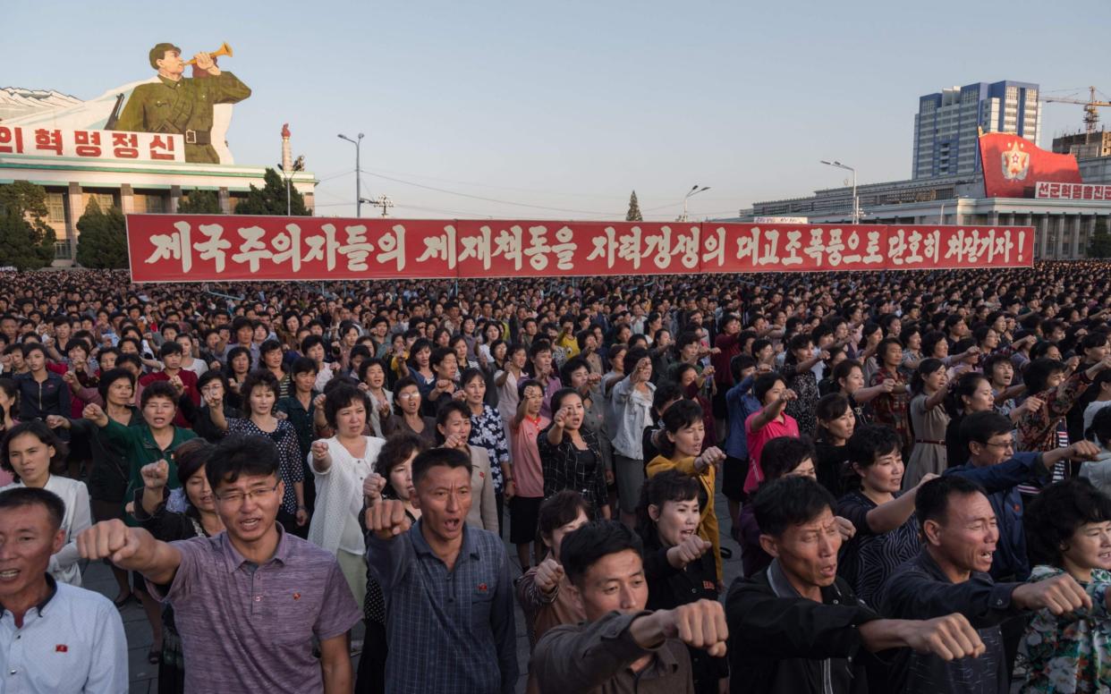 Participants of a mass rally shout slogans as they gather before a banner reading 'let us beat down the sanctions of the imperialists with great progress of self-reliance' on Kim Il-Sung sqaure in Pyongyang on September 23, 2017 - AFP