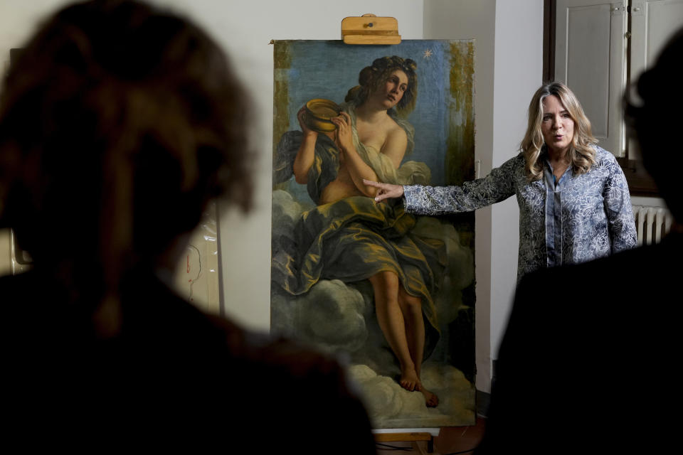 Restorer Elizabeth Wicks stands next to the "Allegory of Inclination", a 1616 work by Artemisia Gentileschi, during a press conference in the Casa Buonarroti Museum, in Florence, Italy, Wednesday, Nov. 9, 2022. Restorers have begun a six-month project on the "Allegory of Inclination" using modern techniques including x-rays and UV infrared research to go beneath the veils painted over the original to cover nudities and discover the work as Gentileschi painted it. (AP Photo/Andrew Medichini)