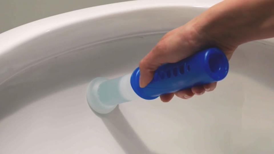 A hand stamping the Scrubbing Bubbles stamp inside a toilet bowl