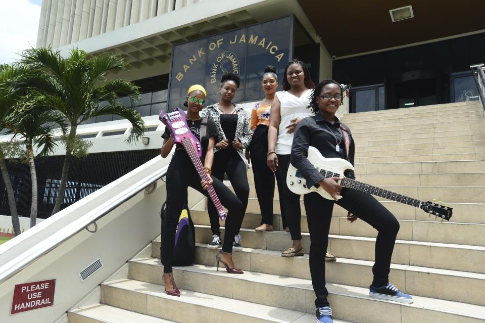 In this June 13, 2019 photo, members of the all-female band ADAHEZ, Chevanese Palmer, from left, Karissa Palmer, Gabeana Campbell, Tashana Barnett and Shadeeka Daughma, pose for a photo on the steps of the Bank of Jamaica, in Kingston. Jamaica’s central bank thinks the country’s economy is doing very well and it is using an instantly recognizable symbol of the island to get this message to the people: reggae music. (AP Photo/Collin Reid)