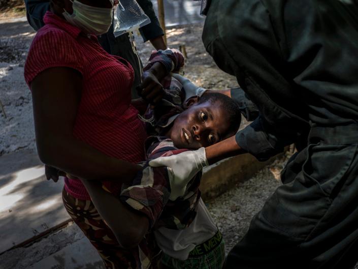 A youth suffering from cholera is helped upon arrival at a clinic run by Doctors Without Borders in Port-au-Prince, Haiti, on Oct. 27, 2022.