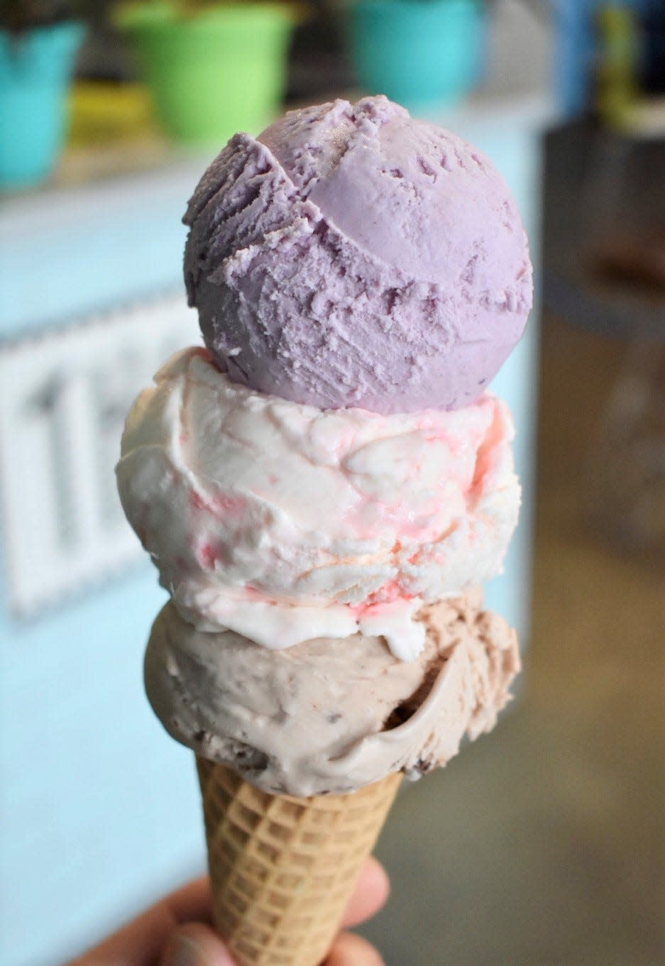 A three-scoop cone featuring Nutella, Peppermint Stick and Purple Yam ice cream from The Hop.