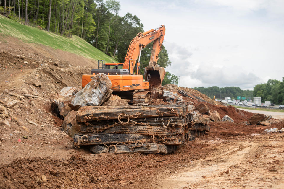 A trackhoe removes rock and debris from a recent blast to accommodate widening along I-26 just south of the Blue Ridge Parkway.