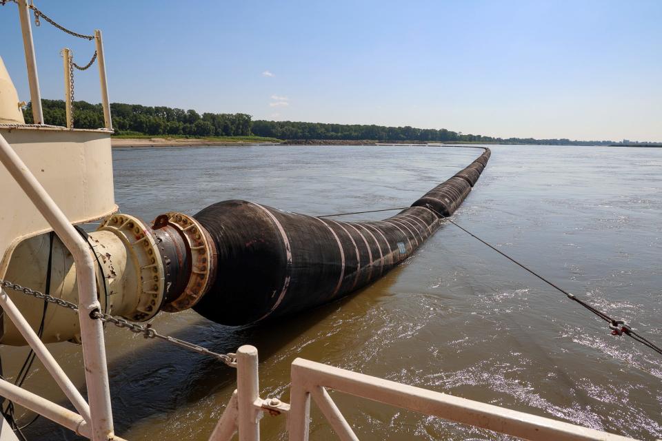 A discharge pipe snakes out from behind the Dredge Potter, a U.S. Army Corps of Engineers vessel working to maintain a channel deep enough for shipping on the Mississippi River.