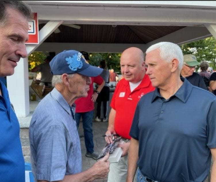 Former Vice President Mike Pence listens to veteran Ray Breslin during a campaign stop in Rye, New Hampshire, hosted by former U.S. senator and ambassador Scott Brown. Also pictured are Brown in the foreground and Pence state campaign manager Matt Mayberry.