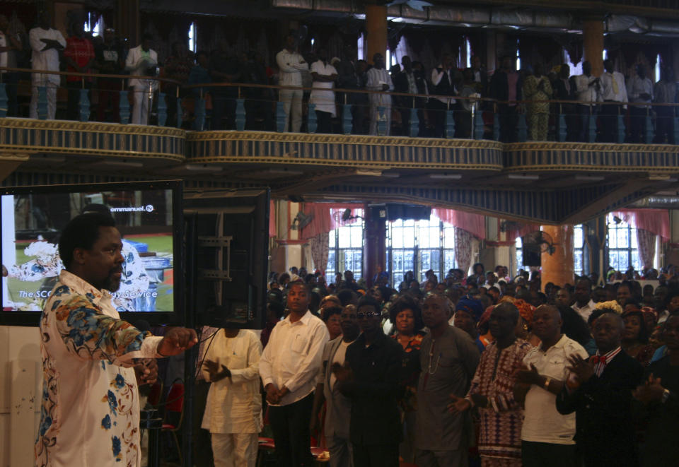 FILE - In this Sunday, Sept. 15, 2013 file photo, T.B. Joshua, left, conducts a service at the Synagogue, Church of All Nations, in Lagos Nigeria. One of Africa’s most popular televangelists, T.B. Joshua, has died, according to his church. He was 57. The Nigerian-born pastor was founder of the mega church, Synagogue Church Of All Nations (SCOAN) which also runs the Emmanuel Television Station in Lagos, Nigeria. The church announced his death in a statement Sunday, June 6, 2021. Joshua was noted for making predictions and for his claims to cure various ailments and to make people prosper through miracles. (AP Photo/Carley Petesch, File)