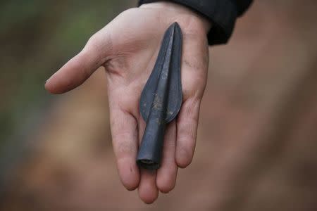 An arrow-head discovered in 2006 by Archaeologists of the University of Cambridge Archaeological Unit, is displayed by one of the team uncovering Bronze Age wooden houses, preserved in silt, from a quarry near Peterborough, Britain, January 12, 2016. REUTERS/Peter Nicholls