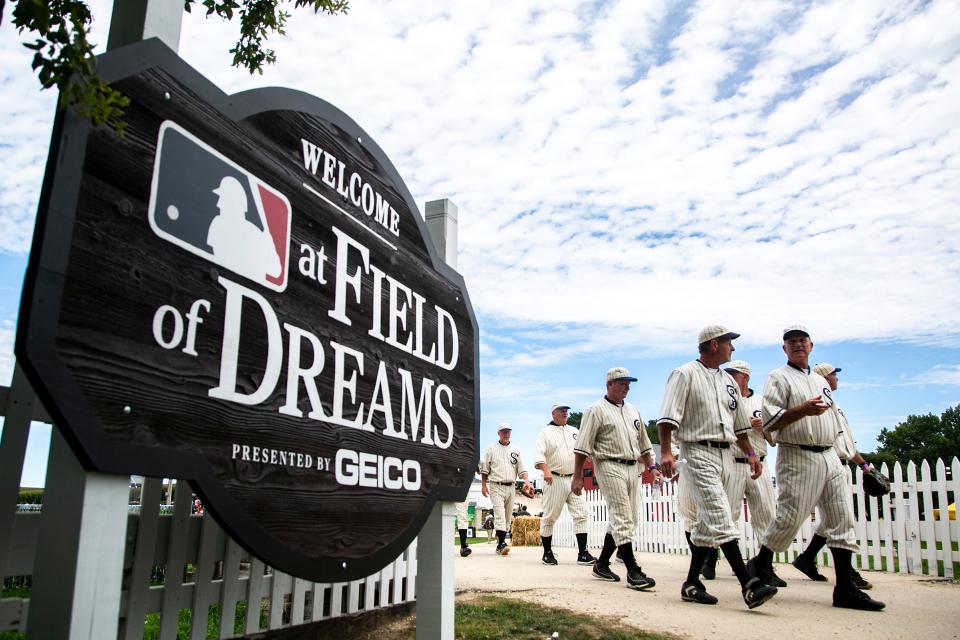 Ghost players walk around the "Field of Dreams" movie site before Thursday's Major League Baseball game between the Cincinnati Reds and Chicago Cubs in Dyersville.