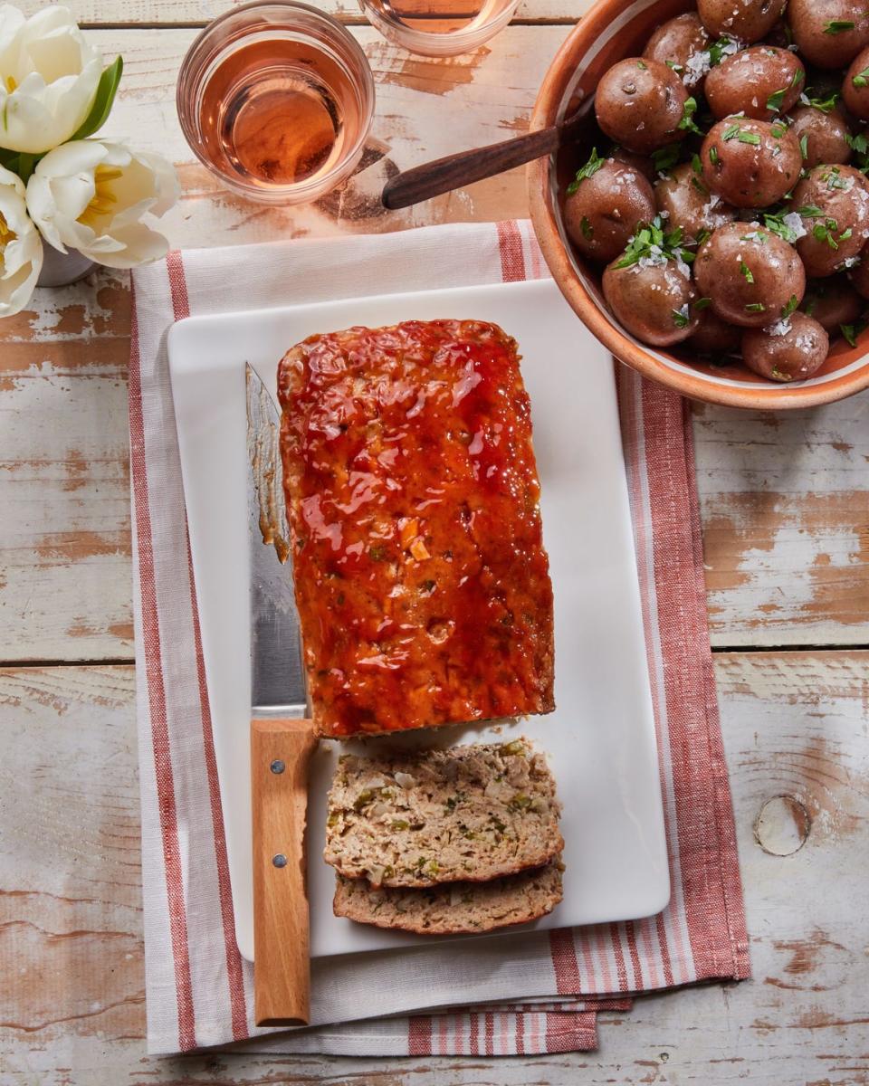 chicken meatloaf on a cutting board with a knife and a brown sugar and ketchup glaze on top