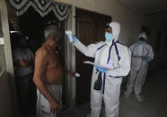 A health worker checks the temperature of a man during a free medical checkup at residential building in Mumbai, India, Thursday, July 2, 2020. Indian Prime Minister Narendra Modi said in a live address Tuesday that the country's coronavirus death rate is under control, but that the country is at a "critical juncture." But since the lockdown was lifted, the caseload has shot up, making India the world's fourth-worst affected country. (AP Photo/Rafiq Maqbool)