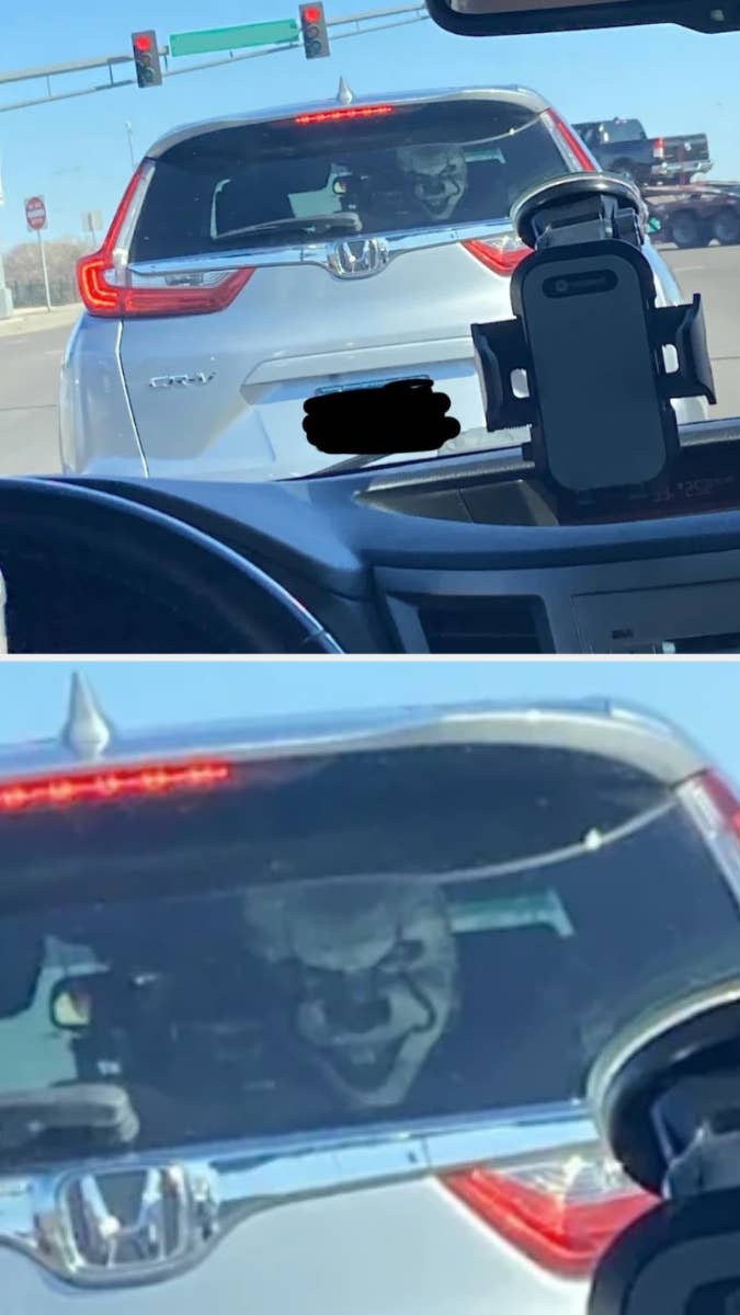 Image of a car's rear with a reflection of a person's face on the trunk, resembling a villainous grin