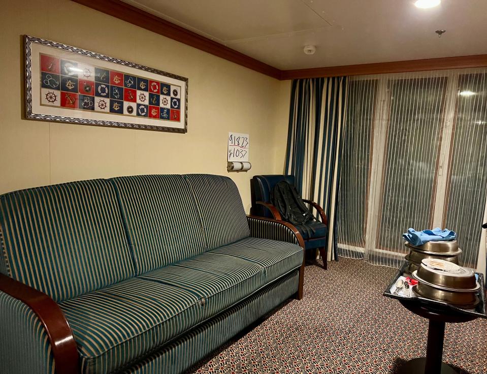 A sitting room with a green-striped sofa, pattered carpet, rectangular wall art, and a small table. 