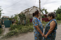 Valentyna Kondratieva, 75, left, is comforted by a neighbor as they stand outside her damaged home Saturday, Aug. 13, 2022, where she sustained injuries in a Russian rocket attack last night in Kramatorsk, Donetsk region, eastern Ukraine. The strike killed three people and wounded 13 others, according to the mayor. The attack came less than a day after 11 other rockets were fired at the city. (AP Photo/David Goldman)