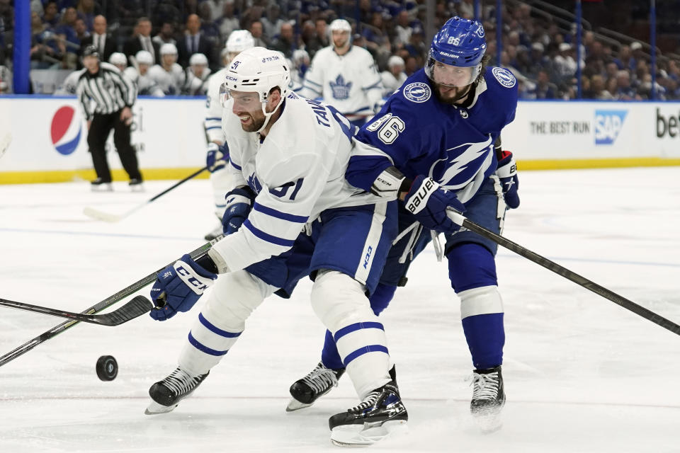 Toronto Maple Leafs center John Tavares (91) and Tampa Bay Lightning right wing Nikita Kucherov (86) battle for the puck during the third period in Game 4 of an NHL hockey first-round playoff series Sunday, May 8, 2022, in Tampa, Fla. (AP Photo/Chris O'Meara)