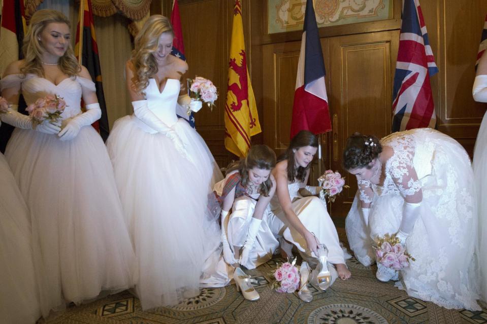 In this Thursday, Dec. 29, 2016 photo, debutantes tired of standing and waiting for a receiving line to form, drop to their knees to pull off their high heels at the International Debutante Ball in New York. (AP Photo/Mark Lennihan)