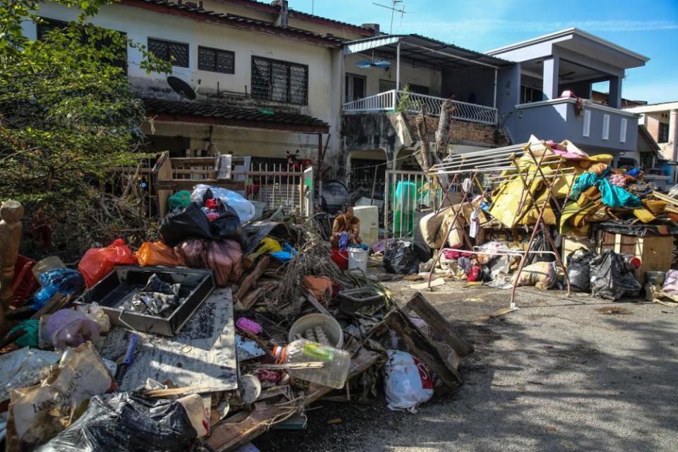 A woman does her laundry outside her home in Taman Sri Muda, Shah Alam December 29, 2021. — Picture by Yusof Mat Isa