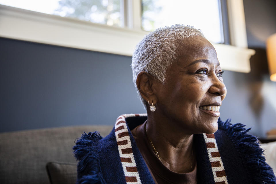 Smiling older woman with short hair, looking away, wearing a textured top with striped details