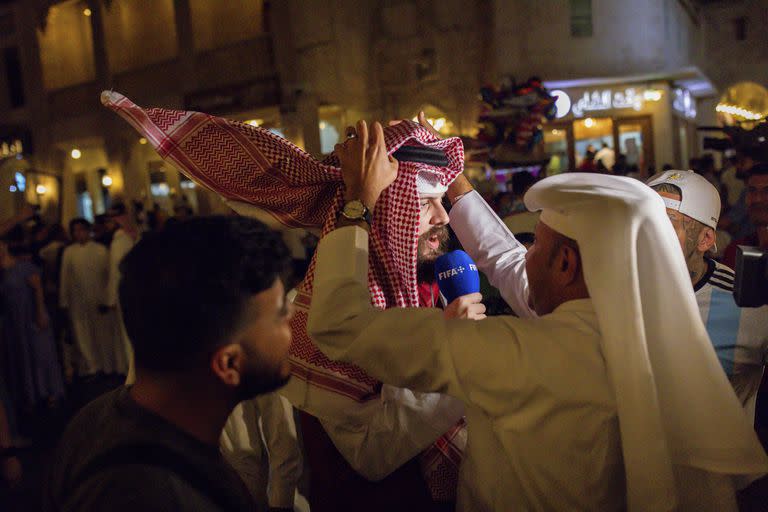 Locales le colocan un ghutra a un periodista en el Souq Waqif de Doha, Qatar. (Tasneem Alsultan/The New York Times)