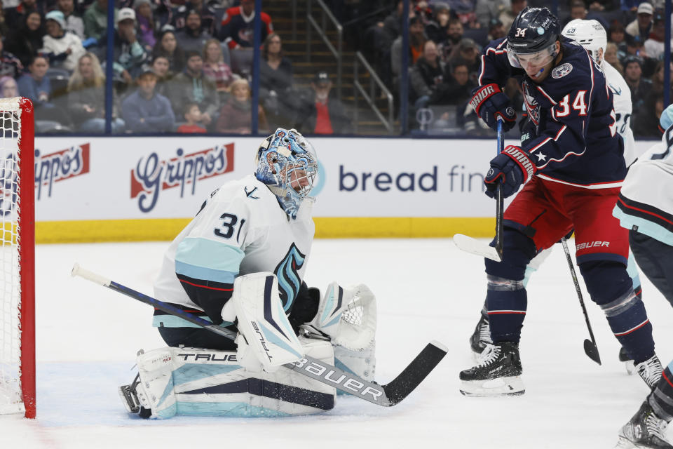 Seattle Kraken's Philipp Grubauer, left, makes a save against Columbus Blue Jackets' Cole Sillinger during the second period of an NHL hockey game Friday, March 3, 2023, in Columbus, Ohio. (AP Photo/Jay LaPrete)