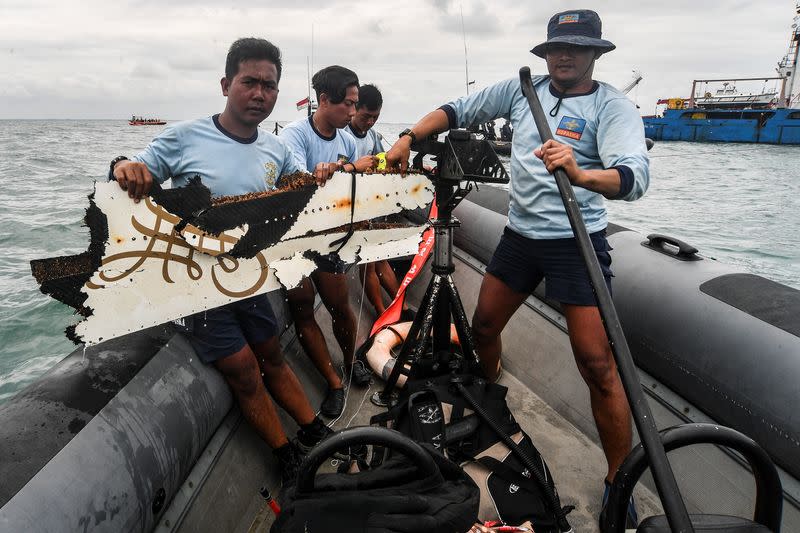 Indonesia Navy members carry recovered debris from Sriwijaya Air flight SJ 182 which crashed into the sea off the Jakarta coast