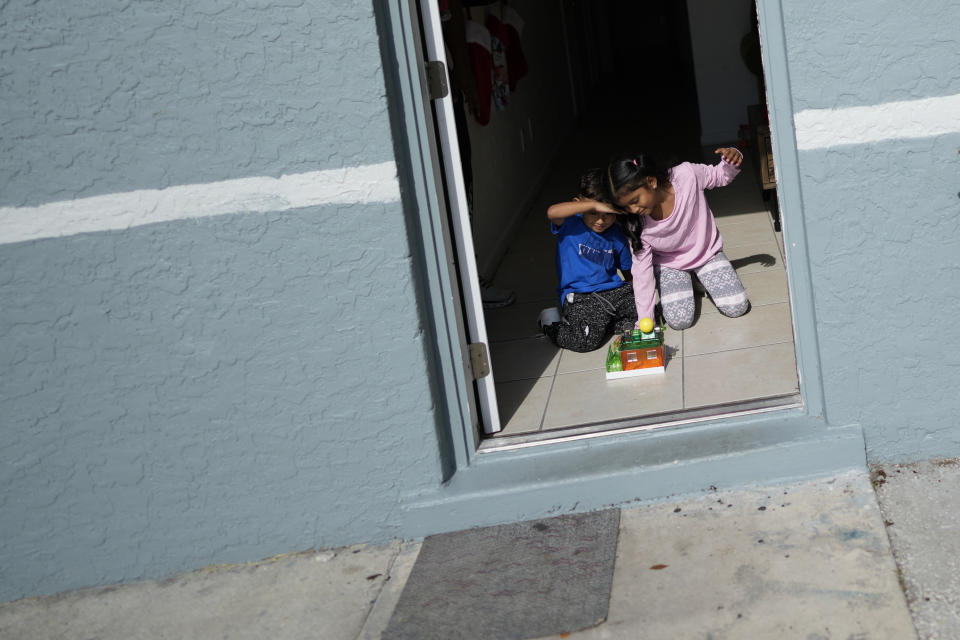 Alexa Llanos, 7, right and little brother Alexis, 3, play together with a solar powered toy house they received as a Christmas gift from the resettlement agency, at the home the family moved into in October 2023, five years after fleeing Venezuela to Colombia to escape death threats and political persecution, in Lehigh Acres, Fla., Dec. 27, 2023. The family is among the first migrants allowed into the U.S. under the Biden administration's new "safe mobility offices," intended to streamline the U.S. refugee process so migrants don't give up and pay smugglers to make the journey north. (AP Photo/Rebecca Blackwell)