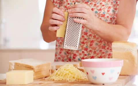 Close up of woman grating cheese in her kitchen - Credit:  MBI / Alamy Stock Photo