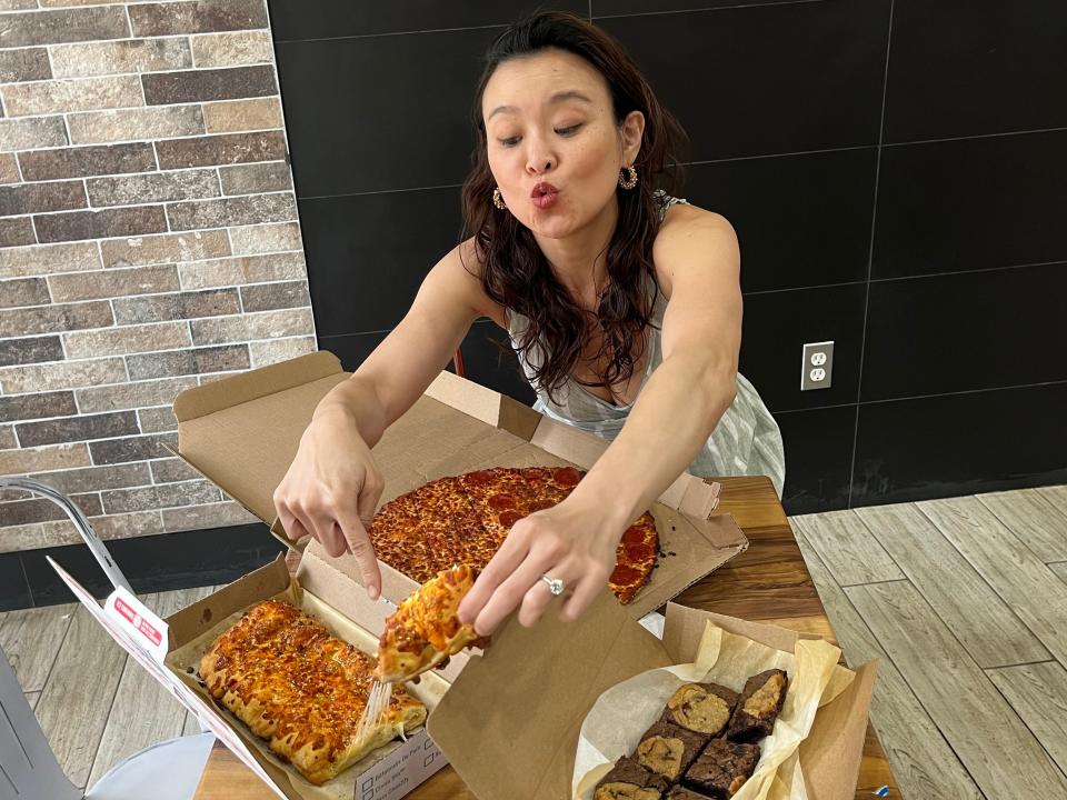 The writer pulls a piece of cheesy bread from a cardboard box