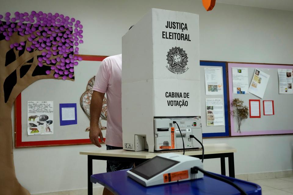 An electoral worker installs an electronic voting machine at a polling station in preparation for the presidential run-off election, in Brasilia, Brazil (AP)