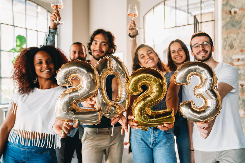 Friends are holding golden balloons to celebrate the new year 2023. New Year's eve party.