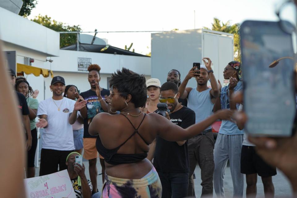 A person voguing with their head turned away from the crowd surrounding them.