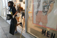 Alycia Barber carries a trash bag through a broken window at Forever 21 at The Pike Outlets on Monday, June 1, 2020, in Long Beach after overnight protests over the death of George Floyd . Floyd died in police custody on Memorial Day in Minneapolis. (AP Photo/Ashley Landis)