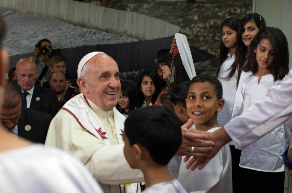 Pope Francis shakes hands with a child during a visit to the Dheisheh refugee camp on outskirts of Bethlehem