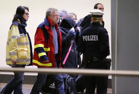 Police and counsellors escort people, believed to be relatives of people who died in the Germanwings crash in the French Alps,, inside the Duesseldorf airport March 26, 2015. REUTERS/Wolfgang Rattay