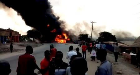 People look towards a fire following a fuel truck collision in Rubirizi