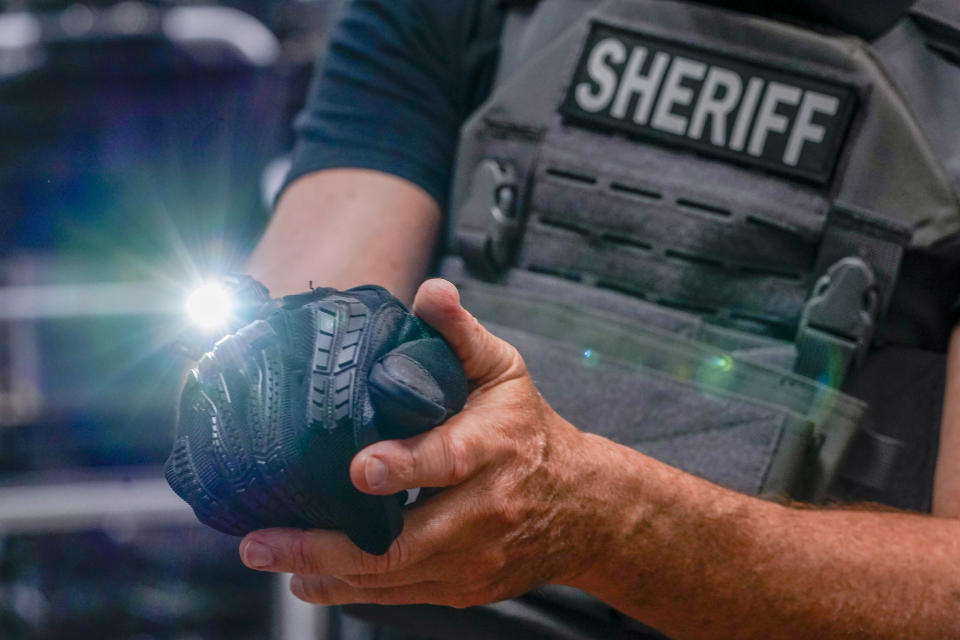 Brad Pedell, a founder of 221B Tactical, demonstrates a hands free glove mounted light system during an interview with The Associated Press, Tuesday, June 14, 2022, at the company's headquarter in New York. (AP Photo/Mary Altaffer)