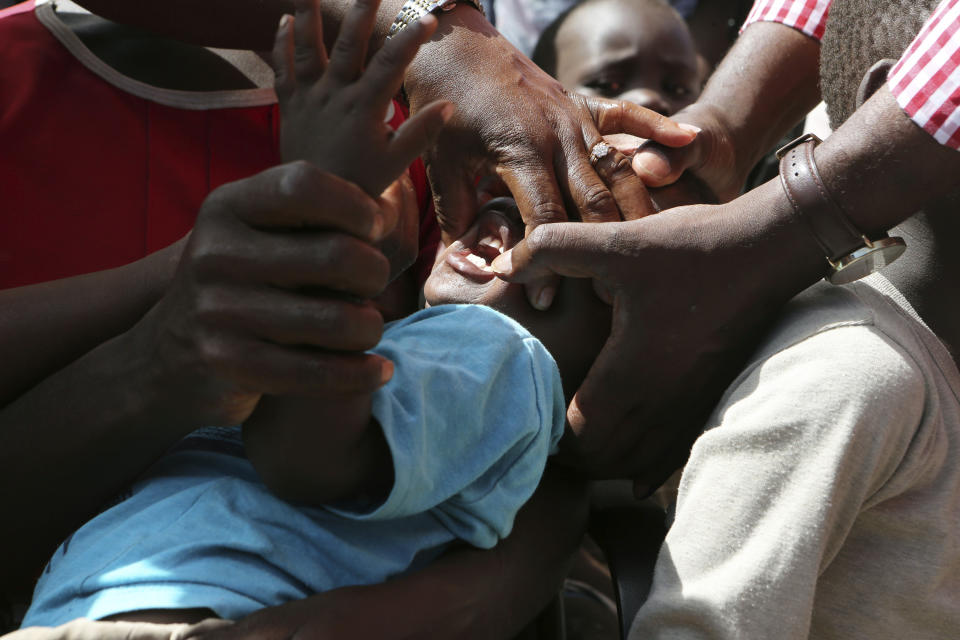 A baby prepares to receive an oral cholera vaccination at a camp for displaced survivors of cyclone Idai in Beira, Mozambique, Wednesday, April 3, 2019. A cholera vaccination campaign is kicking off to reach nearly 900,000 cyclone survivors in Mozambique as officials rush to contain an outbreak of the disease. (AP Photo/Tsvangirayi Mukwazhi)