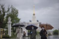 People wearing face masks to protect from coronavirus walk in the rain at VDNKH (The Exhibition of Achievements of National Economy) after reopening in Moscow, Russia, Monday, June 1, 2020. Monday's reopening of retail stores along with dry cleaners and repair shops comes as the pace of contagion has stabilized in the Russian capital that has accounted for about half of the nation's infections. (AP Photo/Alexander Zemlianichenko Jr)