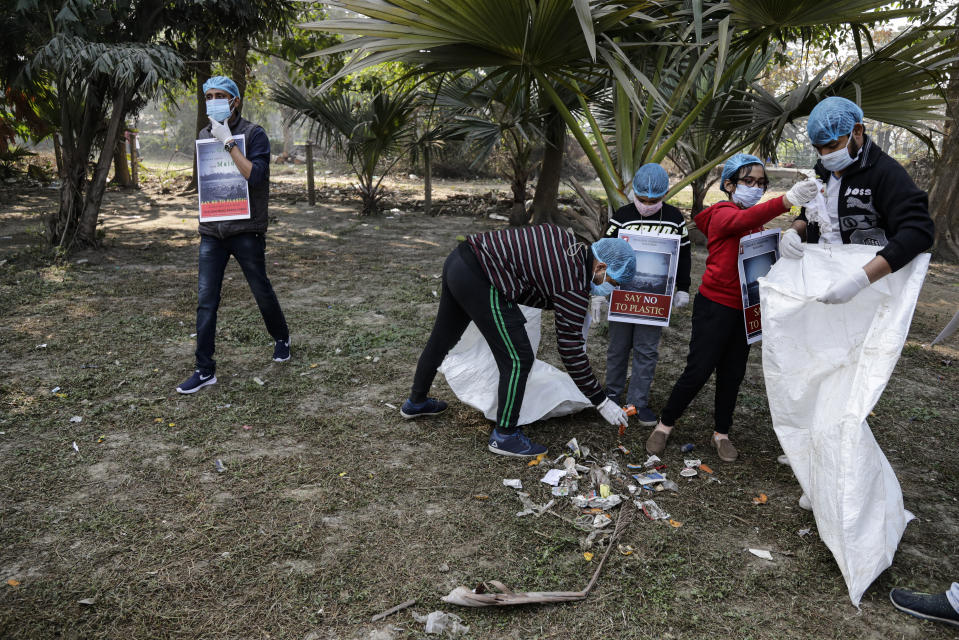 Volunteers wearing face masks as a precaution against the coronavirus clear the debris left over by tourists at Maidan, the city's largest open space in Kolkata, India, Sunday, Jan. 3, 2021. India authorized two COVID-19 vaccines on Sunday, paving the way for a huge inoculation program to stem the coronavirus pandemic in the world’s second most populous country. (AP Photo/Bikas Das)